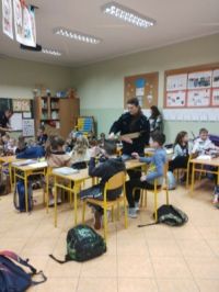 Uczniowie na spotkaniu z policjantem słuchają o bezpieczeństwie podczas ferii